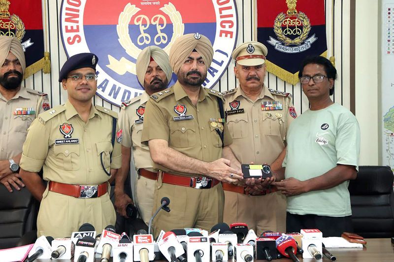 Punjab Police officers handing a recovered mobile phone back to its owner at a press conference