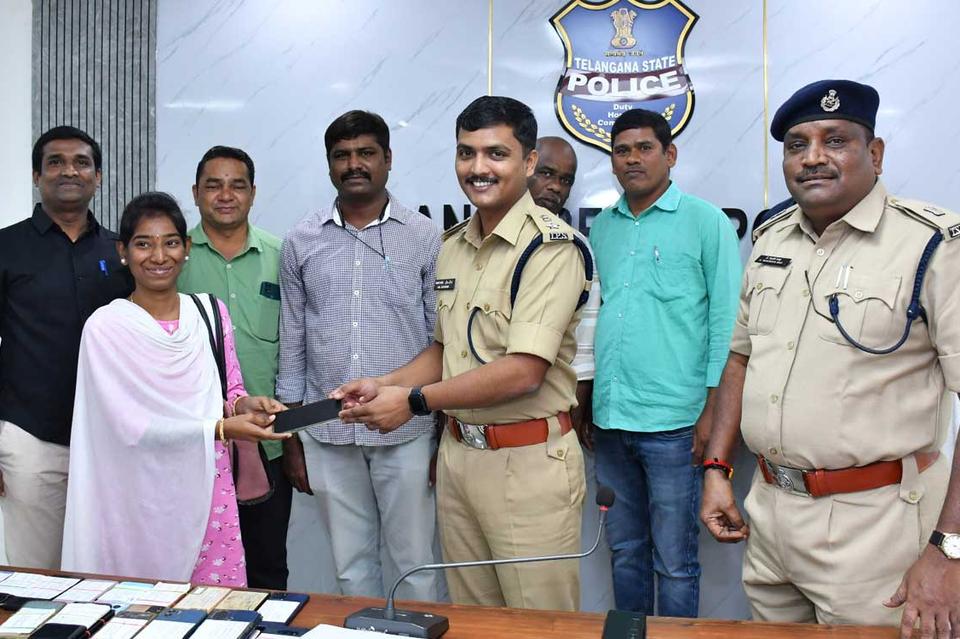 Telangana State Police officers handing a recovered mobile phone back to its owner