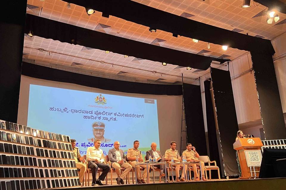 Hubballi-Dharwad Police event on stage, with shelves of recovered mobile phones beside the dais